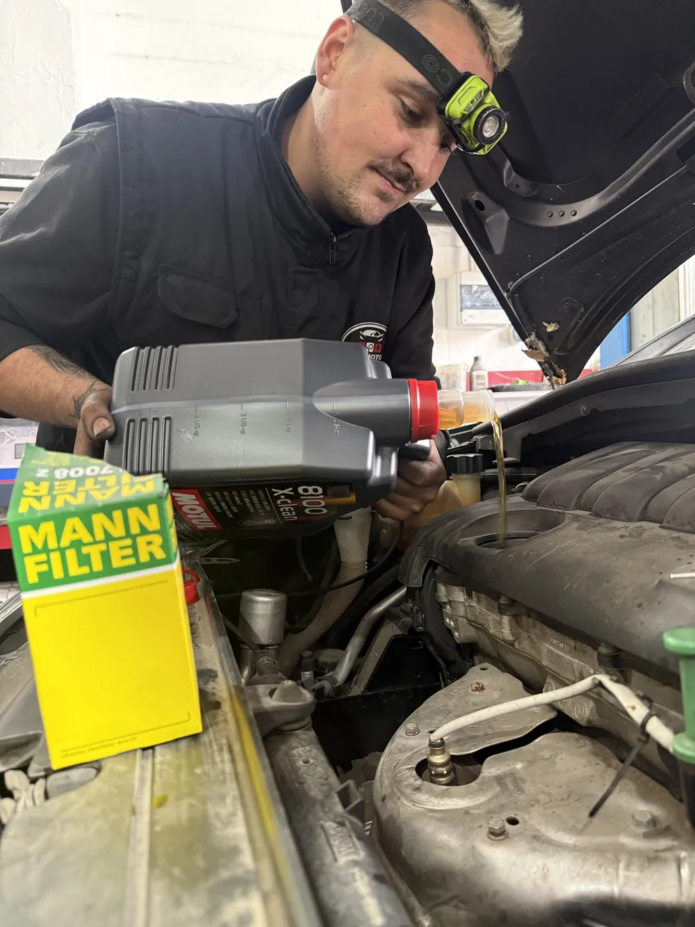 Rafael echando aceite Motul en un motor, con un filtro MANN en primer plano